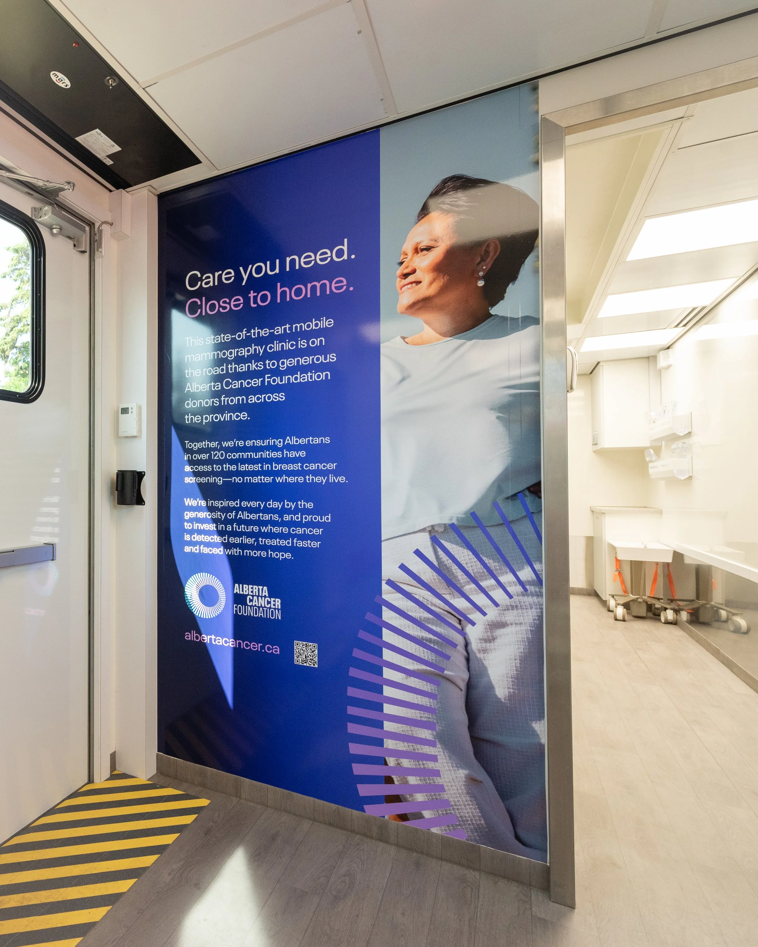 Advertisement for mobile mammography clinic by Alberta Cancer Foundation, featuring a smiling older woman with short dark hair in a white shirt.