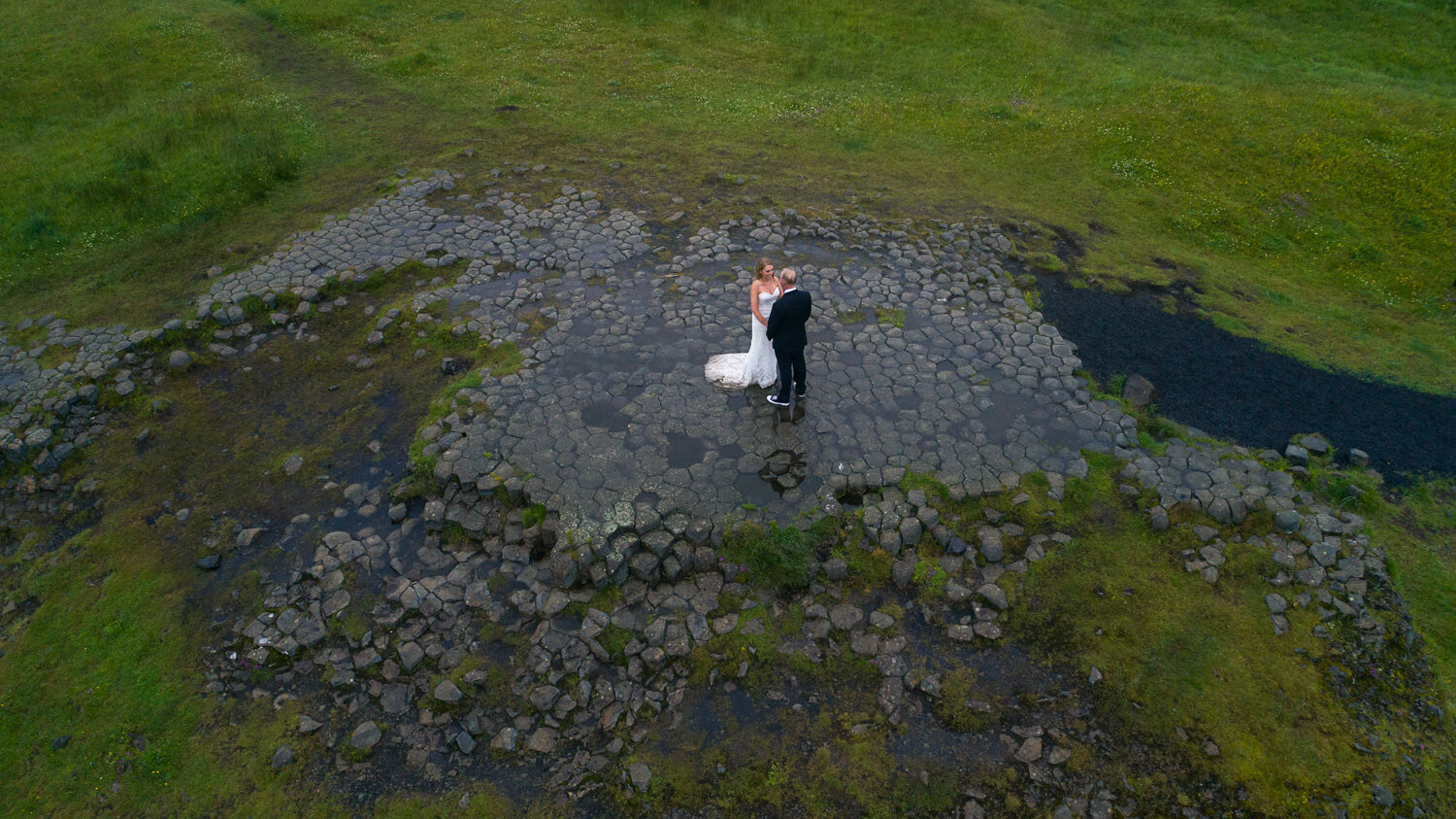 Iceland pre wedding photographer. Drone pre wedding photography of a couple on basalt column floor in Iceland.