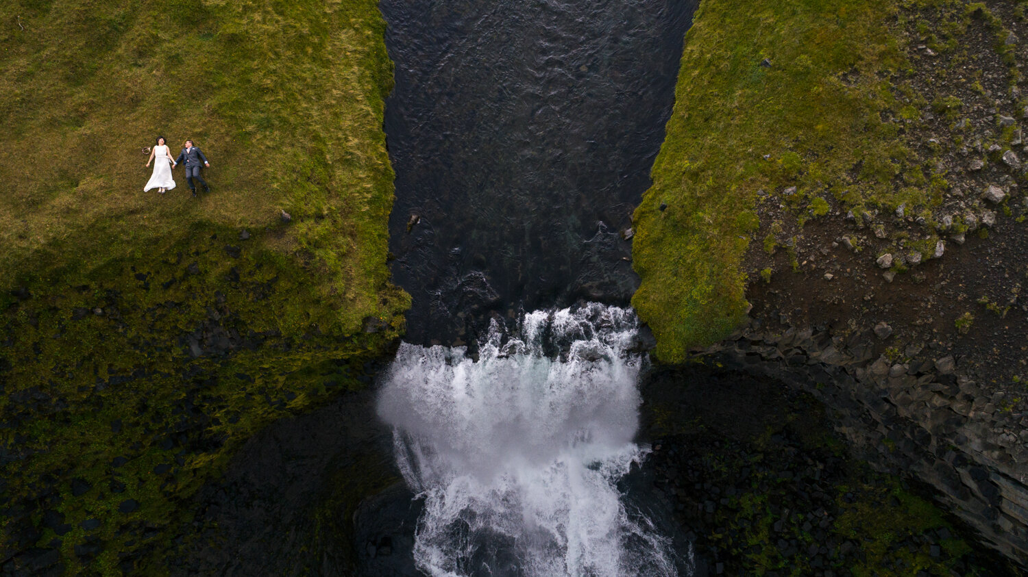 Iceland pre wedding photographer. Drone pre wedding photography of a couple above a waterfall in Iceland.
