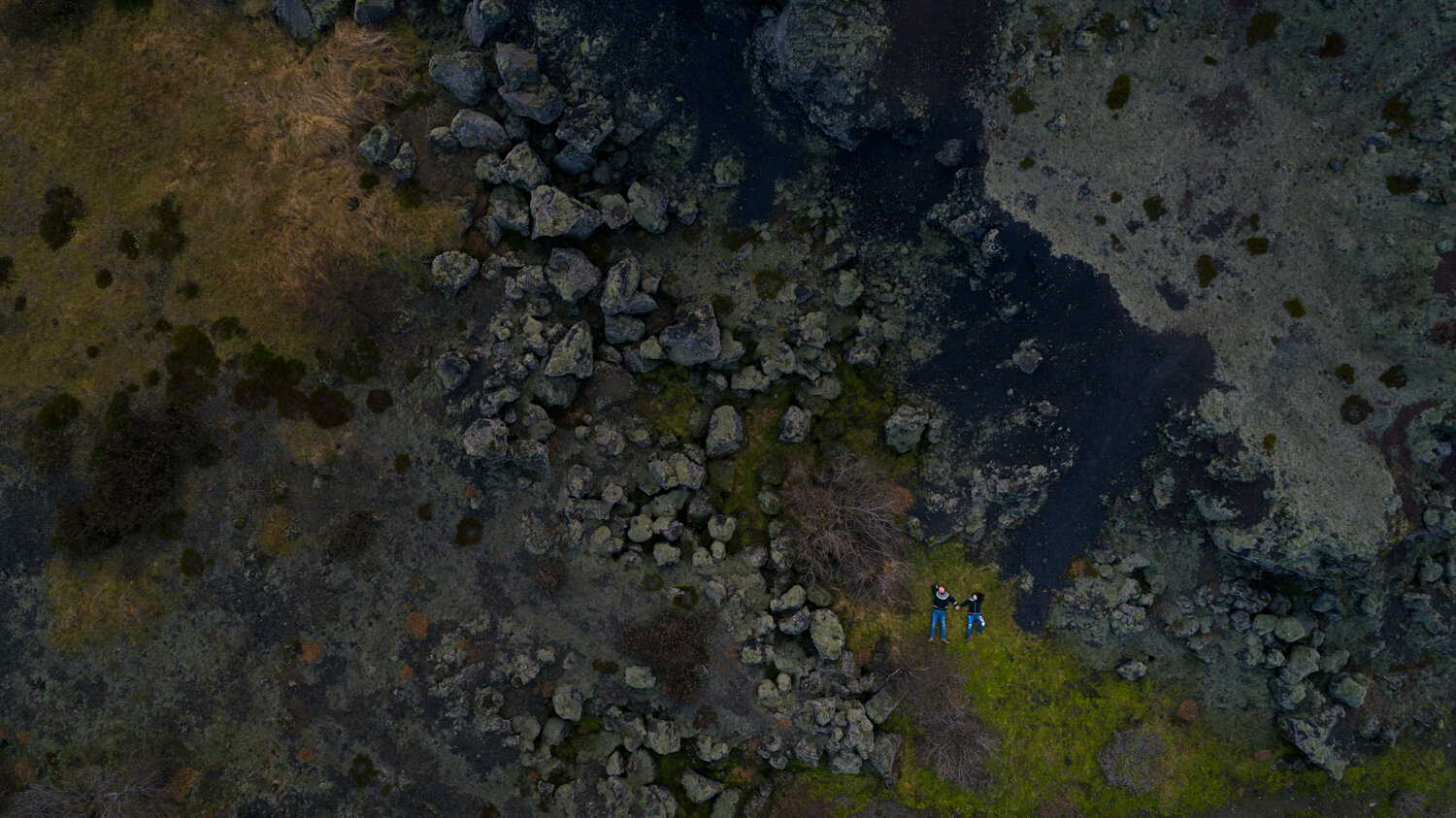 Iceland anniversary photographer. Drone anniversary photography of a couple laying in moss and lava field in Iceland.