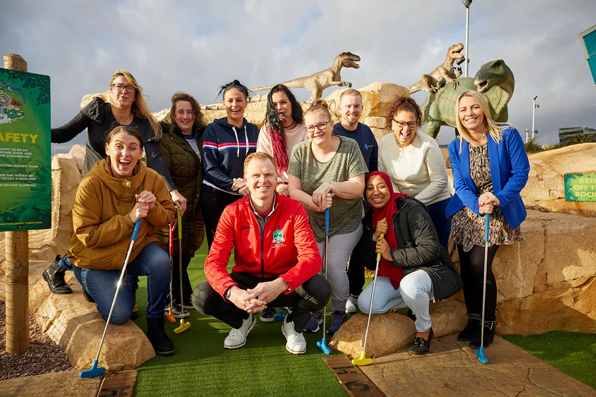 Community representatives including Lisa Brown from Forever Manchester (bottom row, far left), Janet Davies from Salford Foundation – Eccles (back row, far left), Dean Lynch from Challenge 4 Change (back row, third from right) and Kelly Willison from Once Upon a Smile (front row, far right) join Pete Styles, director of golf, at Dino Falls and Trafford Golf Centre (front row, centre) for a celebration of Dino Falls first birthday.