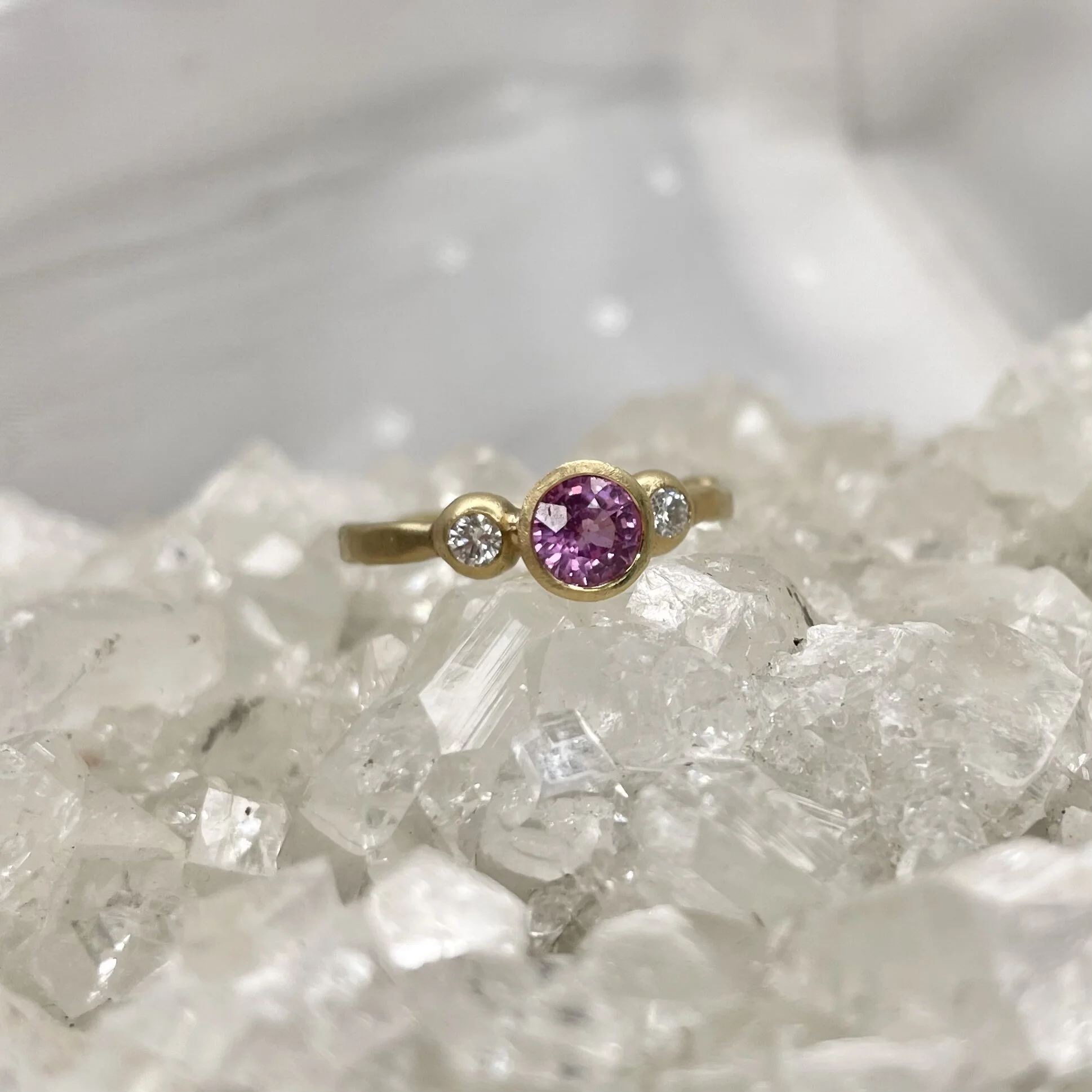 Pink sapphire and diamond three stone engagement alternative bridal ring set in 18ct yellow gold matte finish by Erin Cox Jewellery molten style handmade handcrafted jeweller Exeter Topsham Devon