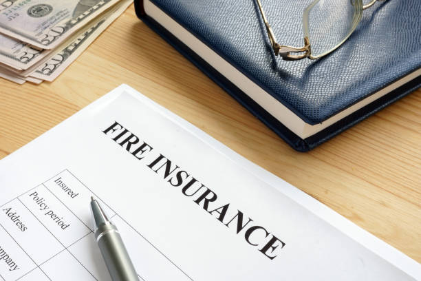 Fire insurance form on a desk with a pen, money, and eyeglasses.