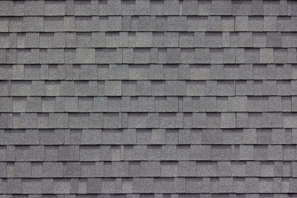Close-up view of gray architectural asphalt shingles arranged in a layered, textured pattern.