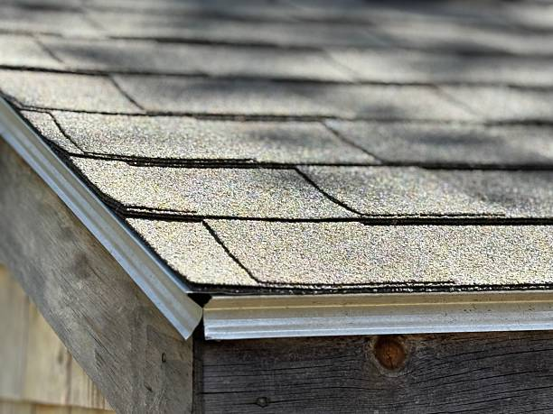 Close-up of an asphalt shingle roof on a wooden structure, showing the layered tabs and metal drip edge.