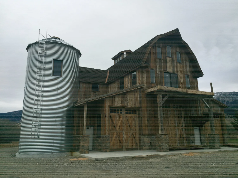 Rustic barn with a gambrel roof design, wood exterior, and attached metal silo.