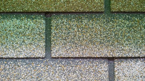 Close-up of traditional 3-tab asphalt shingles in a speckled brown and gray color pattern.