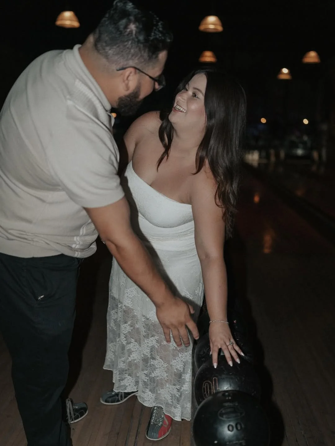A couple looking at each other, picking a black ball for bowling at Highland Park Bowl.