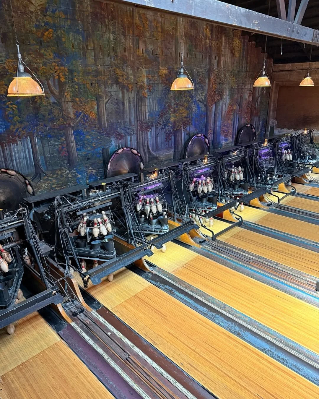 Wooden bowling lanes with classic mechanical pinsetters in action at Highland Park Bowl