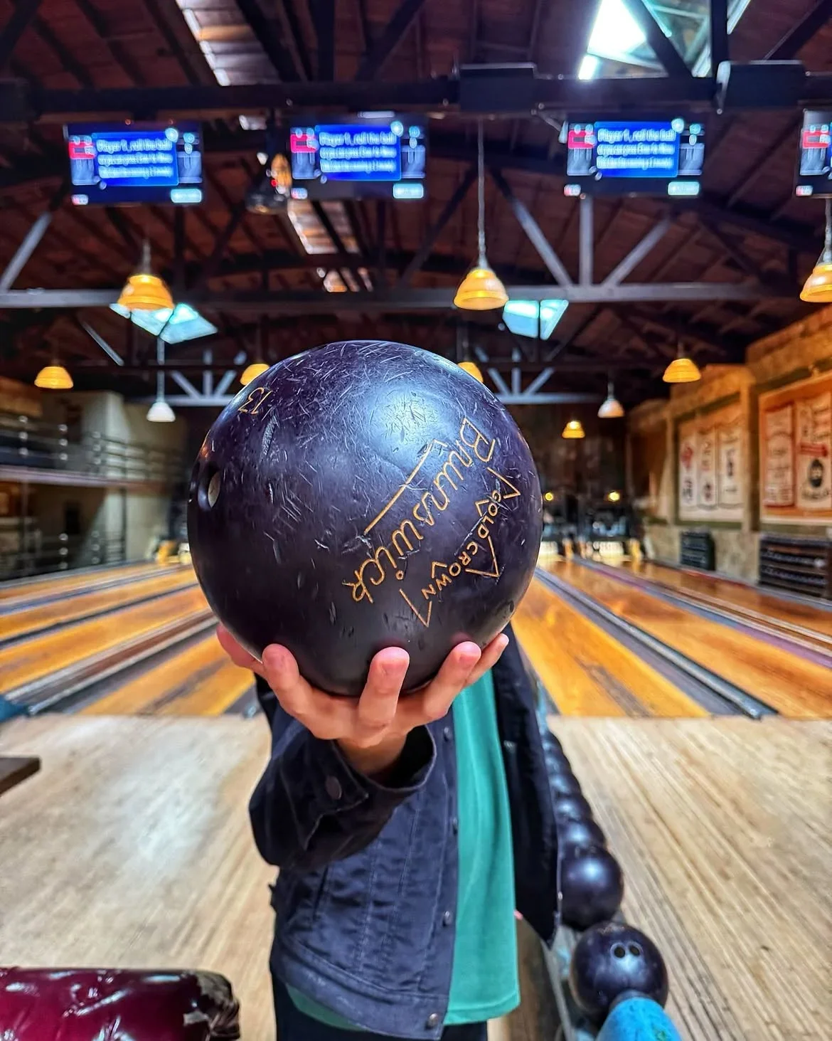 Close-up of a Brunswick bowling ball held up against the historic lanes at Highland Park Bowl.