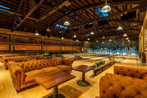 Interior of Highland Park Bowl featuring restored wooden bowling lanes, vintage architecture, leather seating, and warm lighting.