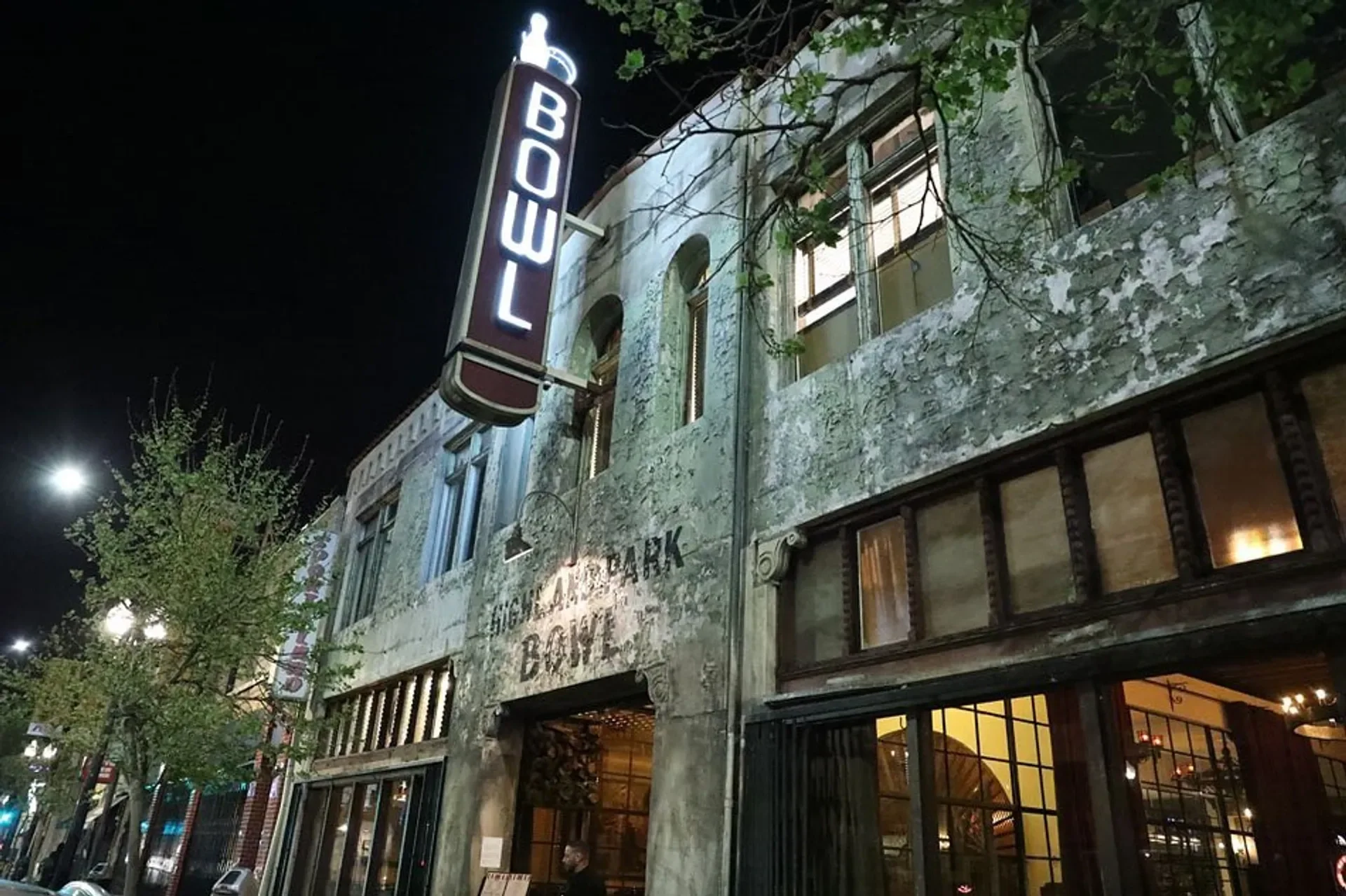 Highland Park Bowl's iconic neon sign illuminating the historic building exterior at night in Los Angeles.