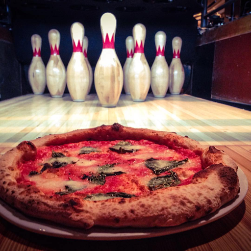 Fresh margherita pizza served beside the restored wooden bowling lanes at Highland Park Bowl.