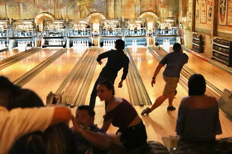 A cozy bowling setup at Highland Park Bowl, with people bowling and having fun in a warm light setup.