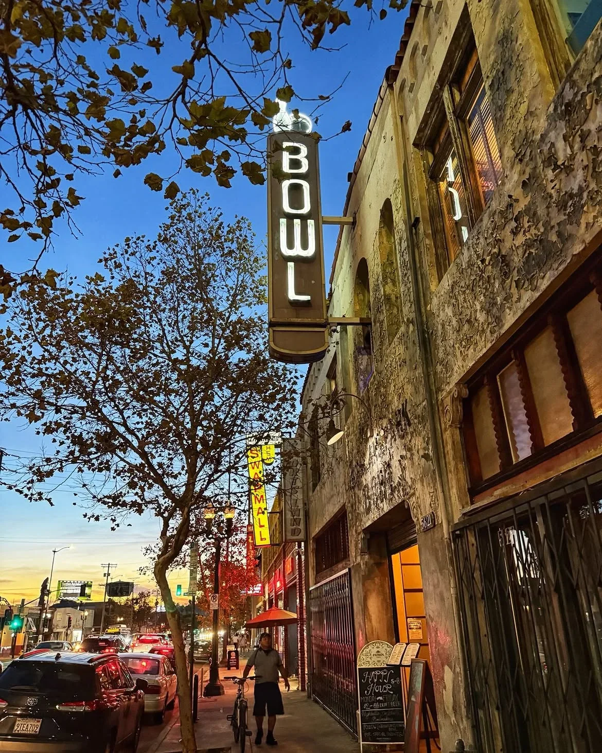 Exterior view of the vintage Highland Park Bowl with neon BOWL sign on the historic building at dusk.