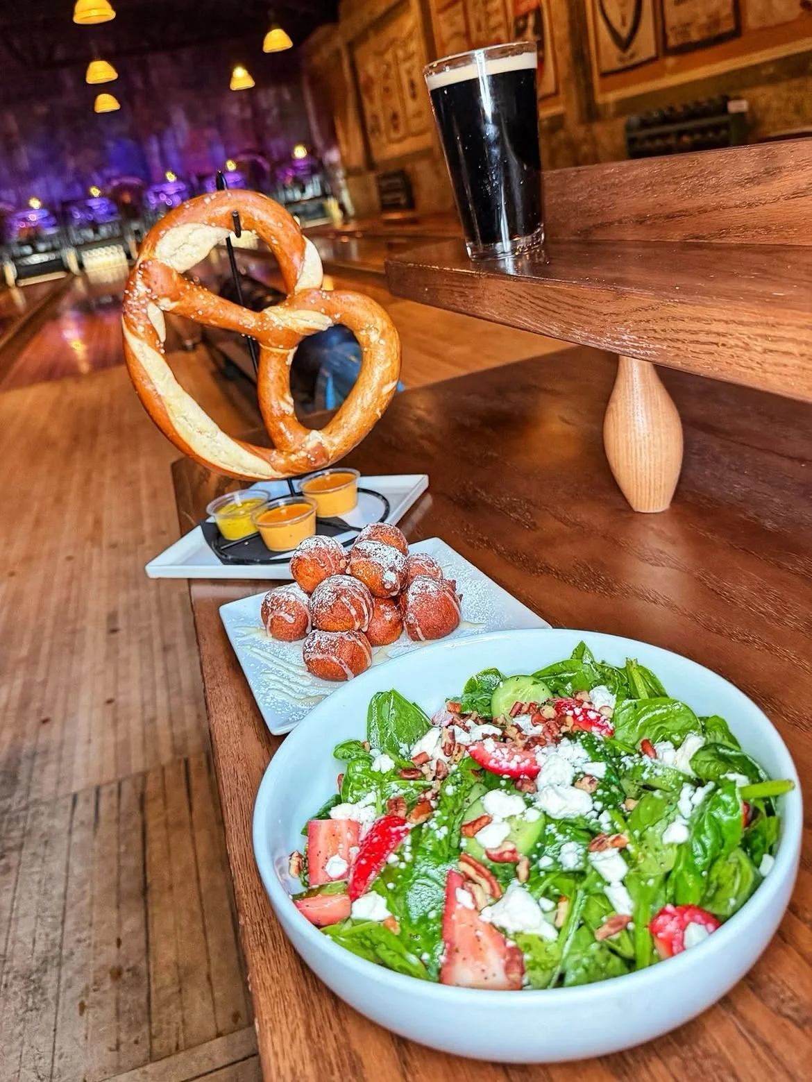 A shared salad, giant soft pretzel, and dark beer enjoyed at Highland Park Bowl.