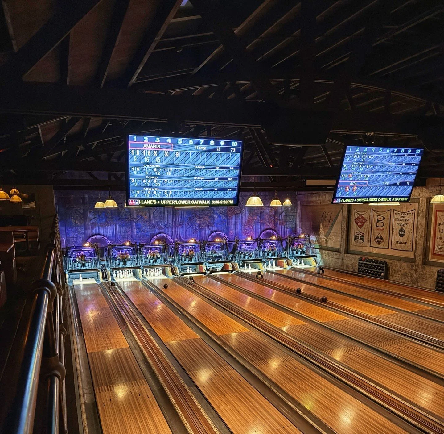 Wooden bowling lanes inside Highland Park Bowl with scoreboards and warm lighting.