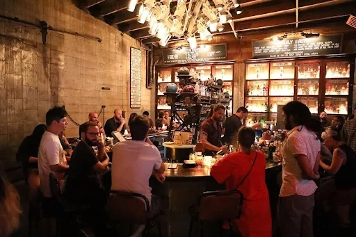 Friends gathered around the historic bar at Highland Park Bowl, enjoying handcrafted cocktails in a lively, vintage setting.