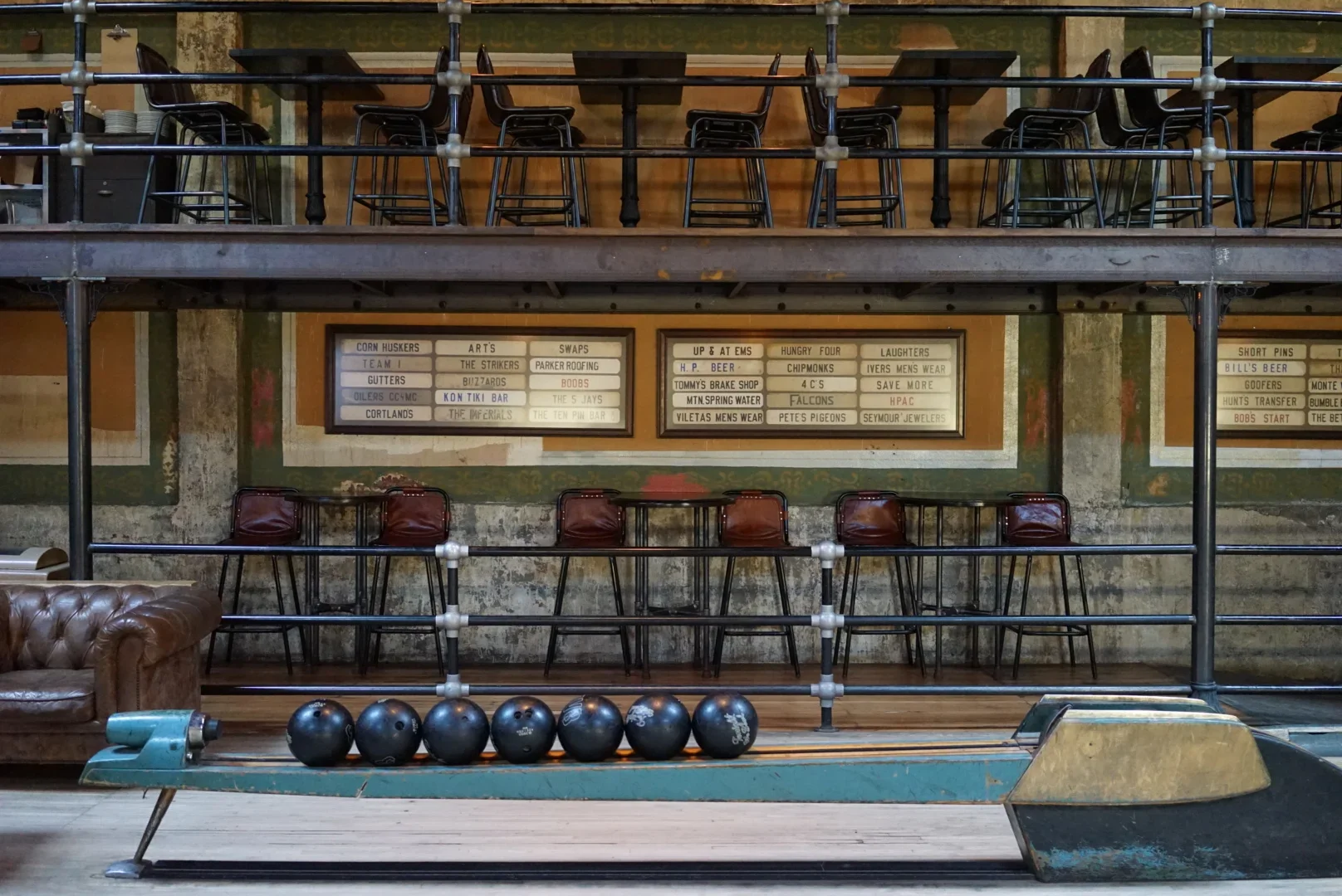 A bowling alley, Highland Park Bowl, with balls laid out in a single file and chairs and tables.