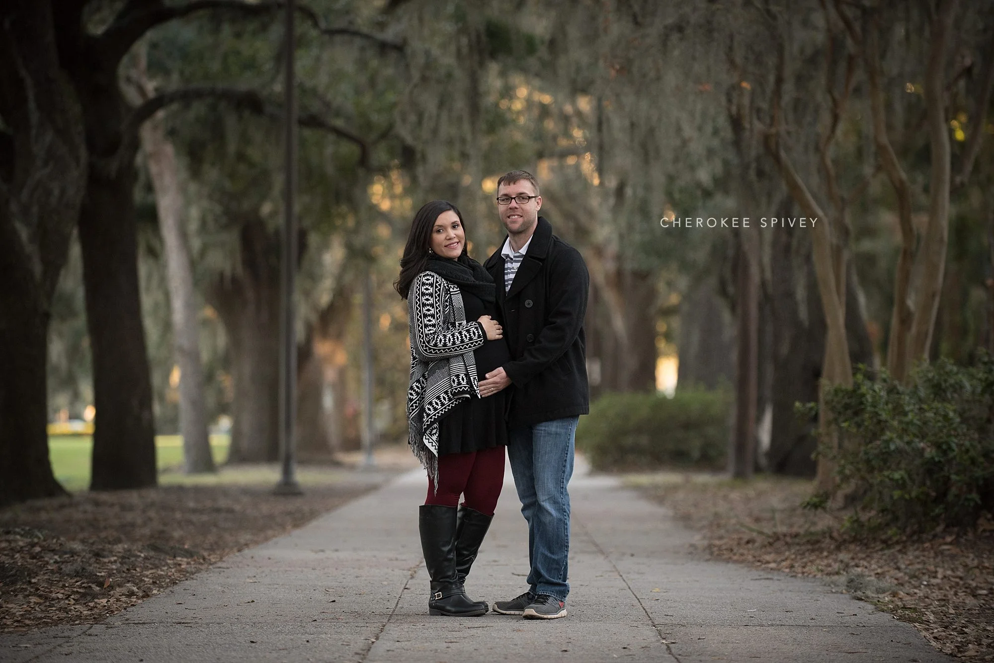 beautiful moss draped trees of Savannah, Georgia is the backdrop for a couple dressed in winter clothes embracing