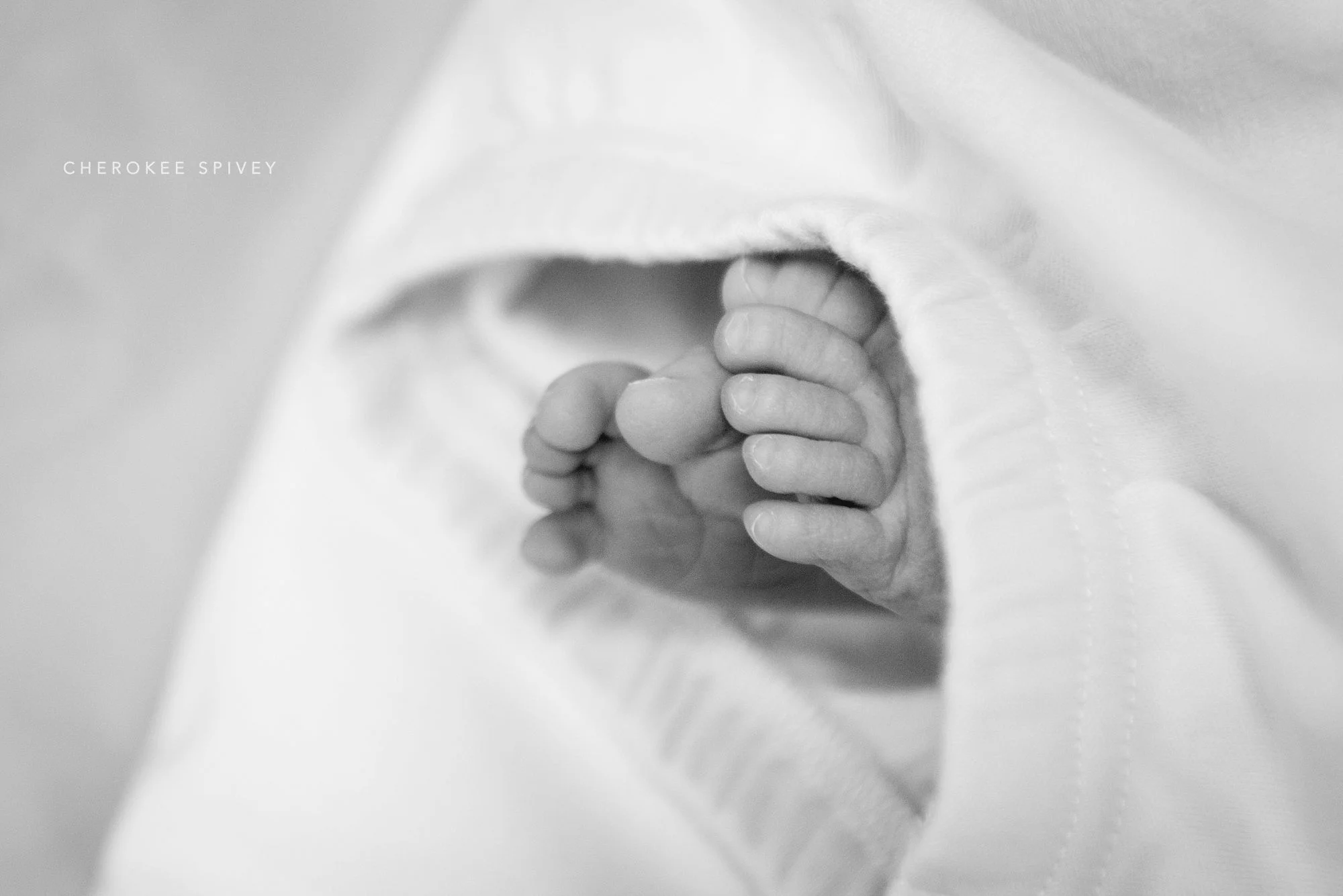 Tiny little baby toes are sticking out from under a soft fleece blanket