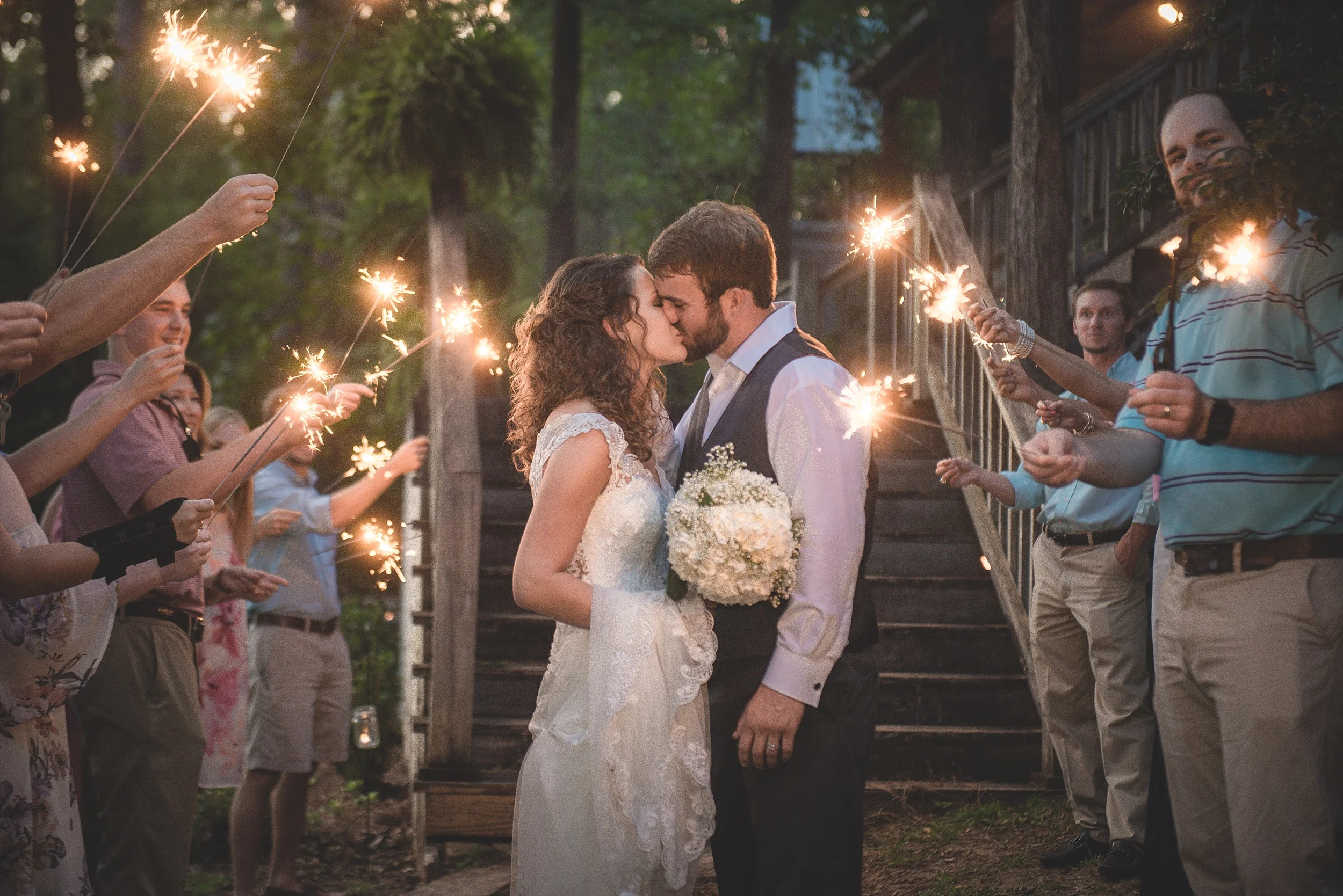 Sparkler exit as couple kiss in a tunnel of people and twinkles