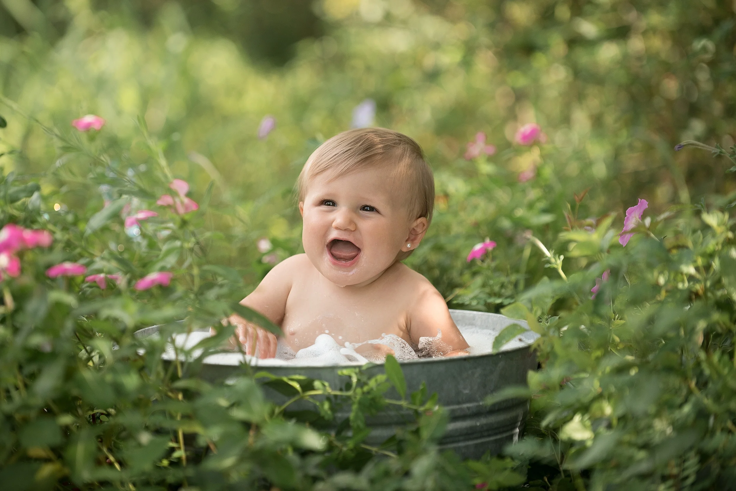one year old girl splashes in a bubble bath outdoors