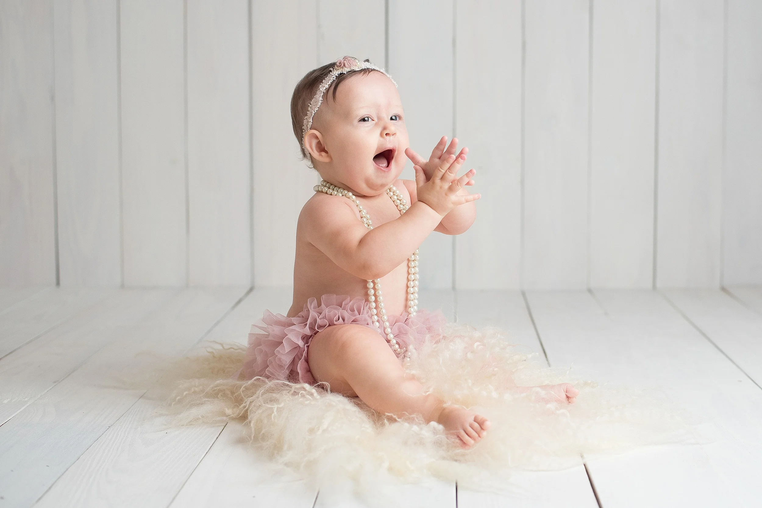 9 month old baby girl in pink tutu claps and laughs