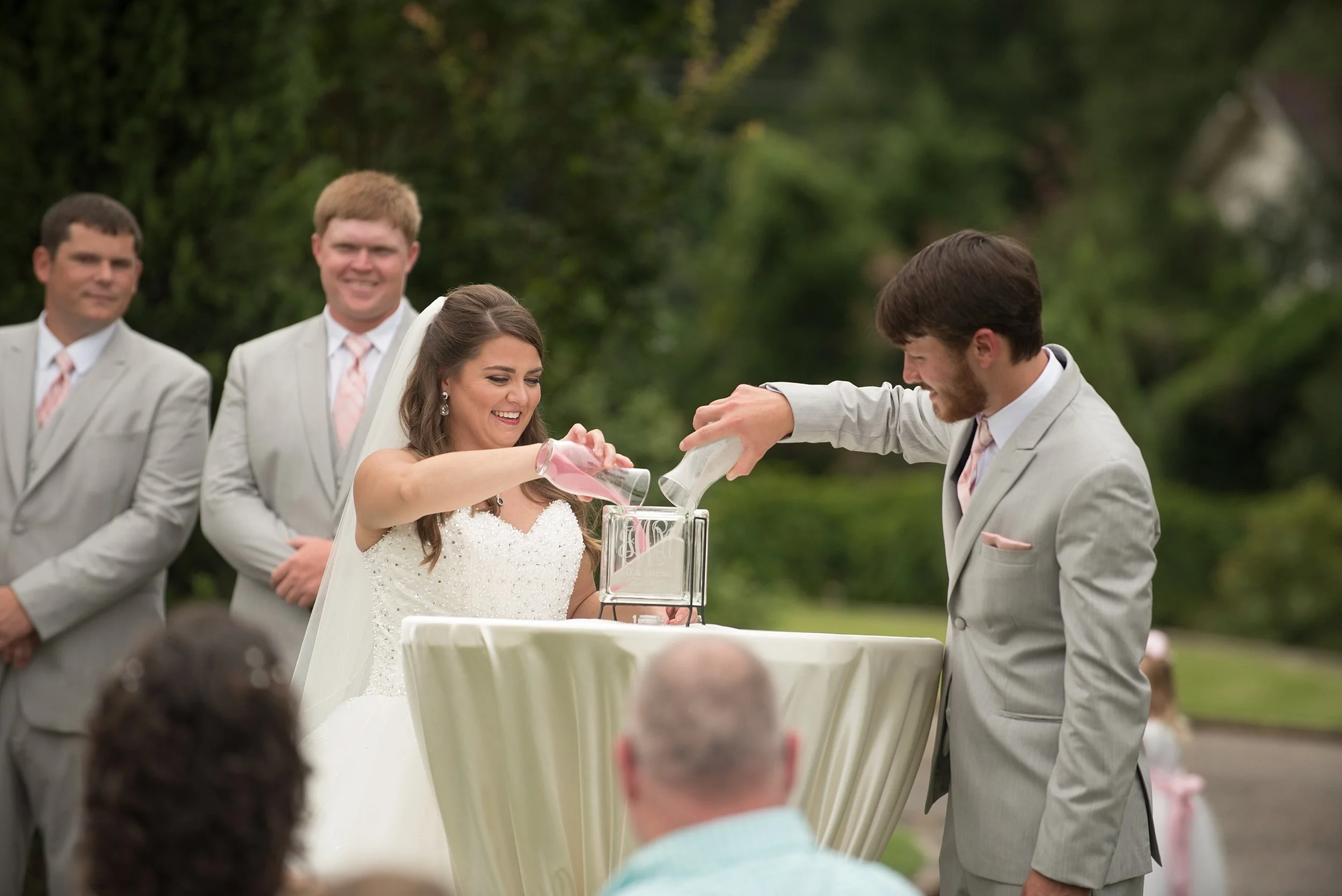 Bride and groom perform sand ceremony at their outdoor wedding