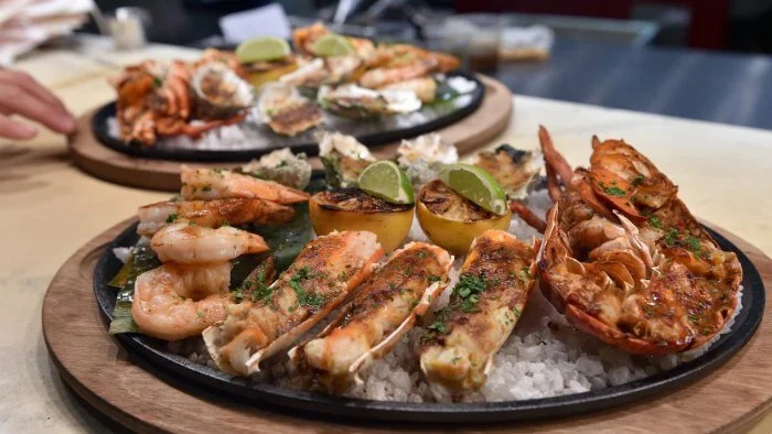 The shellfish platter at International Smoke is prepared on a wood grill and drizzled with miso butter. Other signature items include the Shaking Beef, Braised Jamaican Oxtail and Smoked St. Louis Cut Pork Ribs served American barbecue style. Photo:…