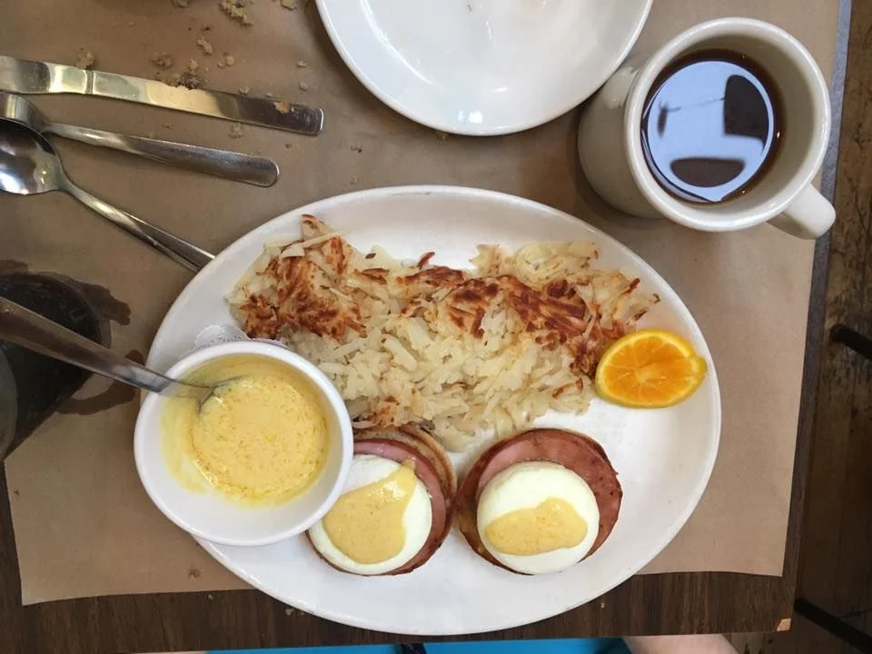 Eggs Benedict with sauce on the side; hash browns