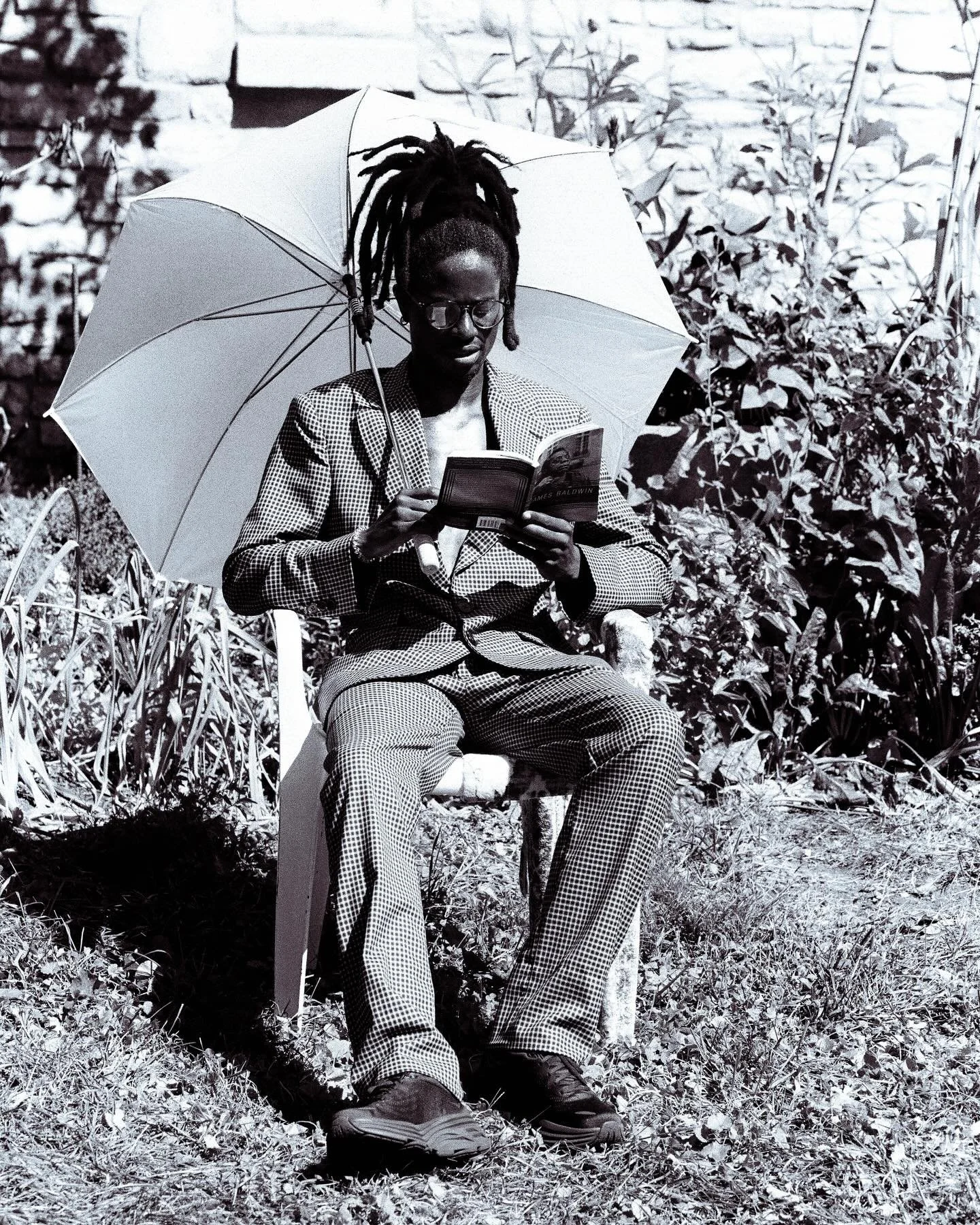 @malcolmalexis in Mabuhay Gardens SS25 reading The Fire Next Time by James Baldwin documented by @bijansosnowski
