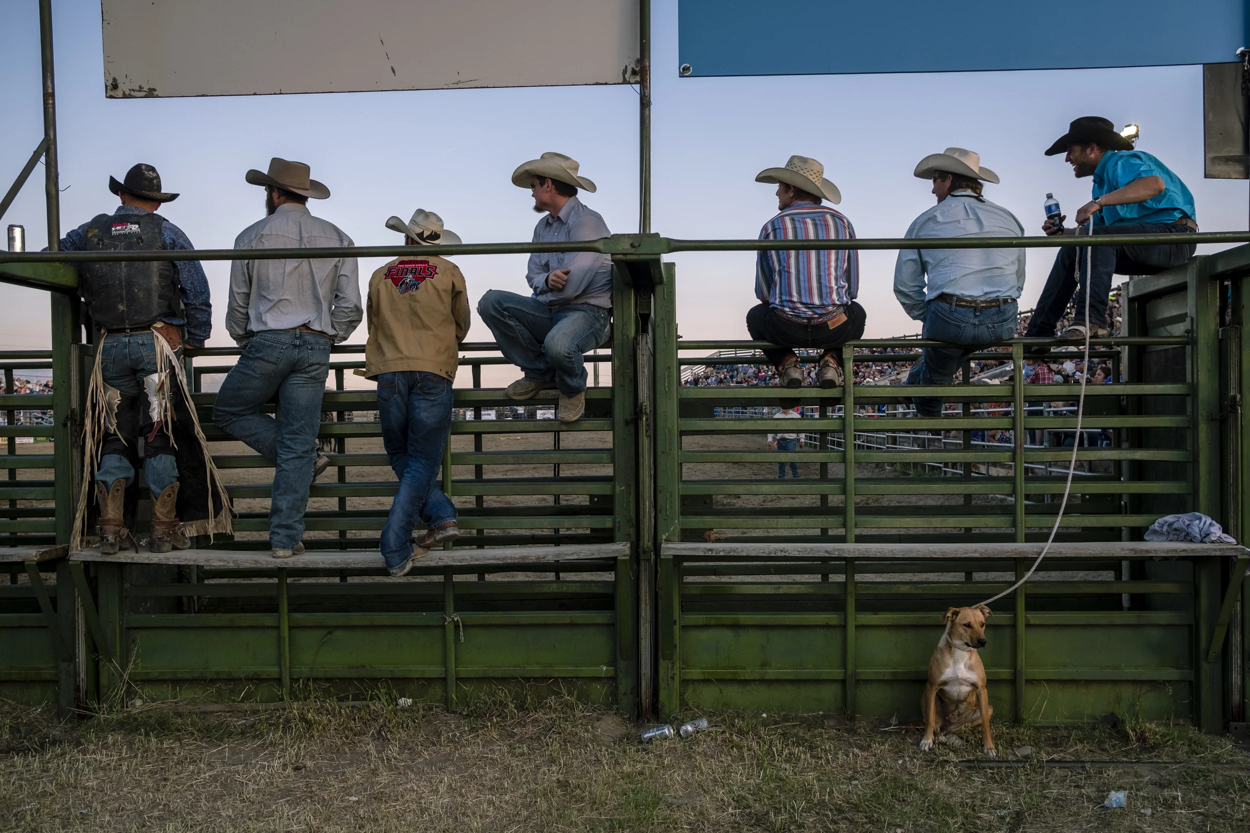 Cowboys who had already completed their ride watch the final bull rider at the Ennis Rodeo in Ennis, MT, on July 4, 2018. From 3700 Miles: Just Passing Through