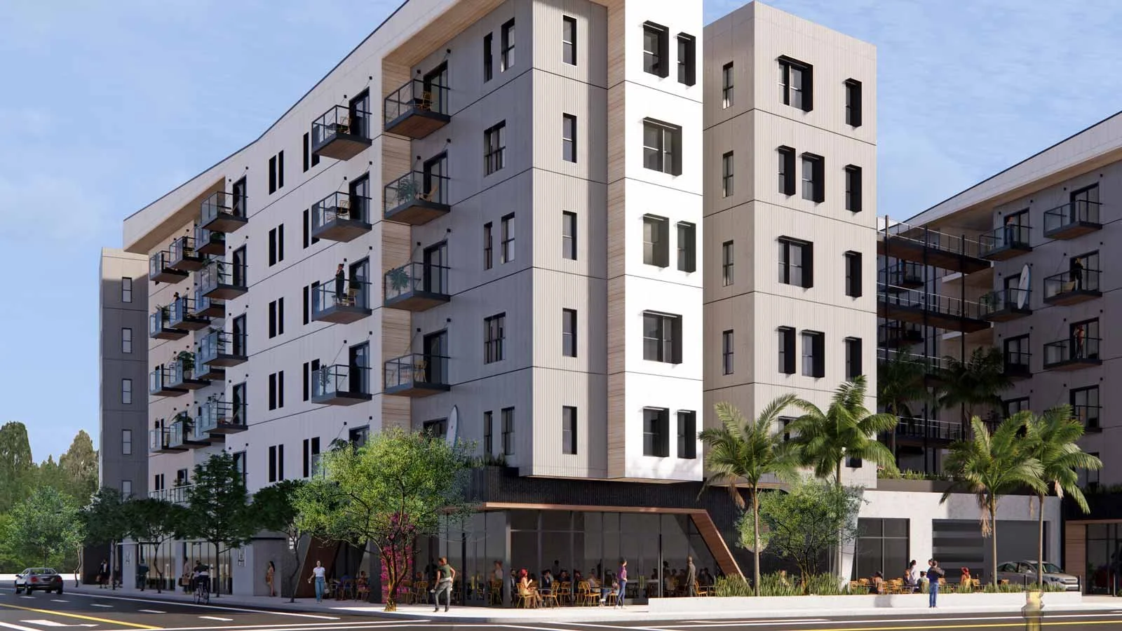 Modern multi-story apartment building with balconies, greenery, and street-level café tables.