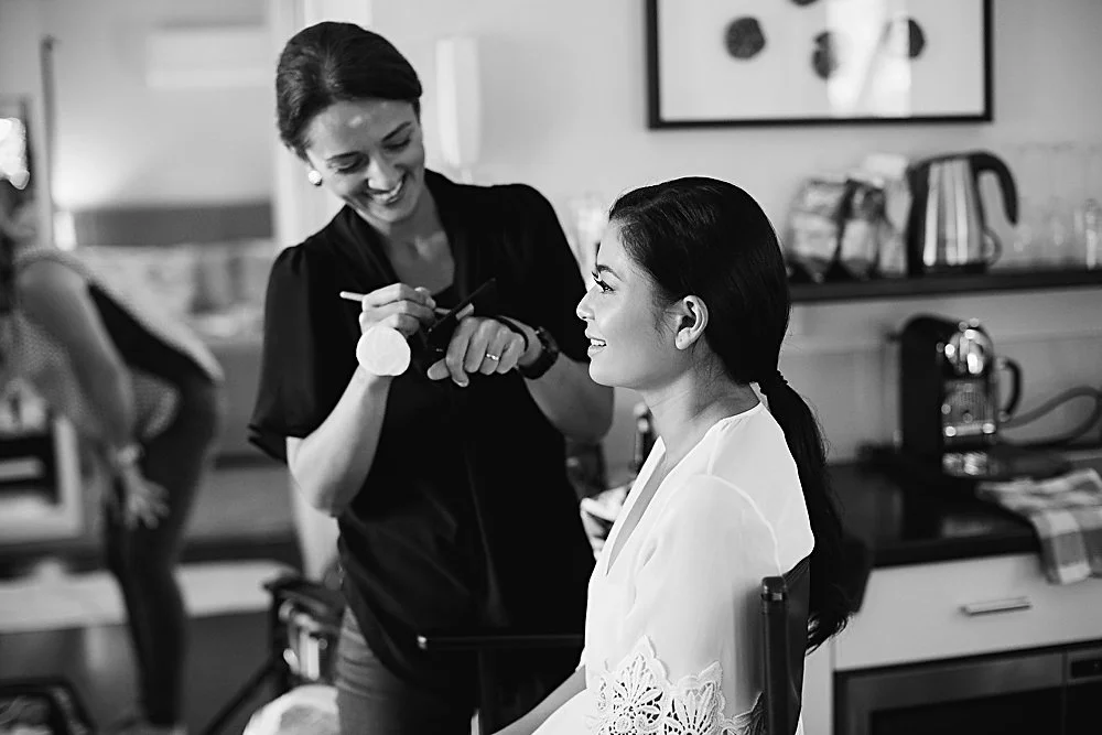A timeless black and white photograph of international artist Tasleema Nigh applying makeup, capturing the intentional and calm atmosphere of her professional beauty services.