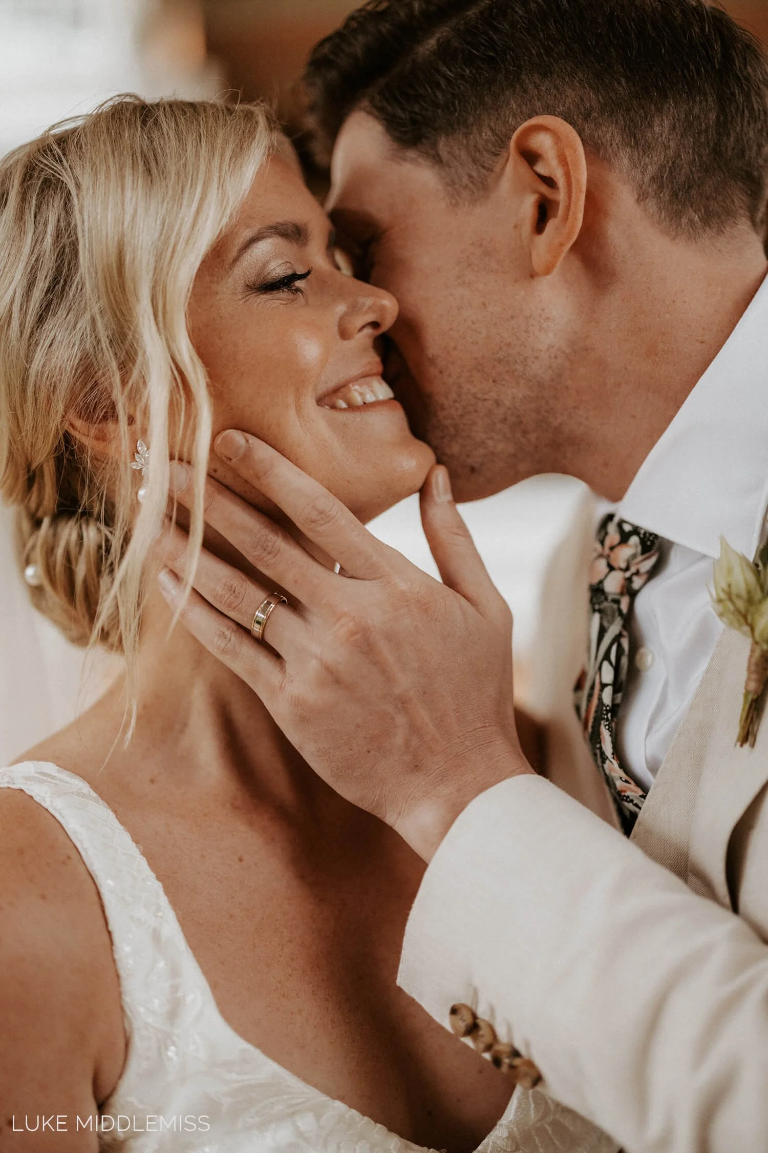 A close-up of a bride with luminous, glowy skin during a wedding hug, featuring professional long-wear bridal makeup by a Sunshine Coast specialist.