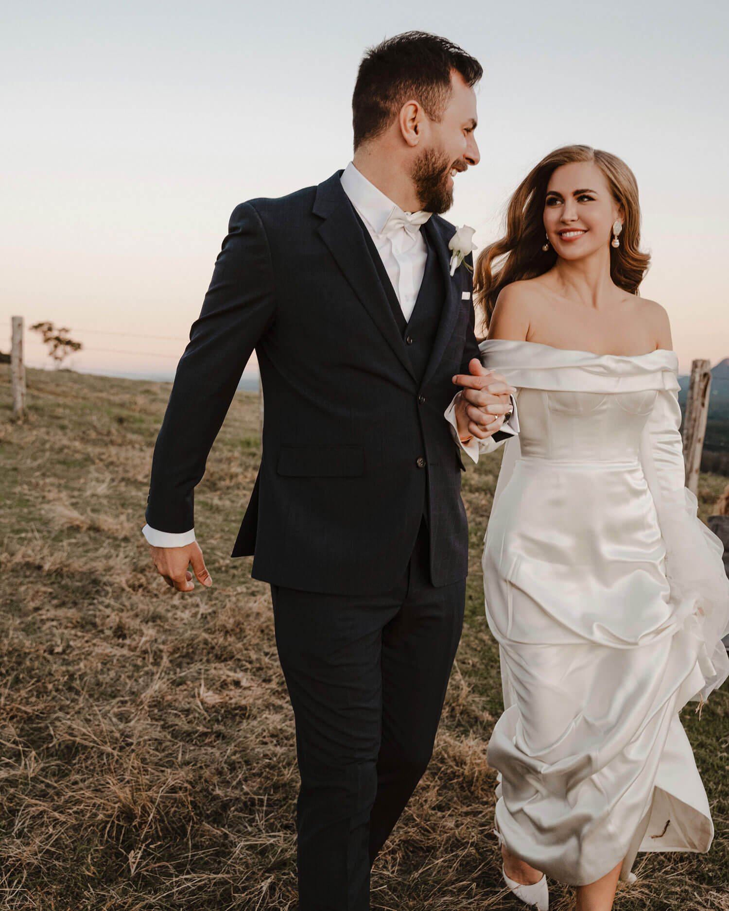 A happy couple running through the Maleny hills, showcasing long-wearing, radiant bridal makeup that stays flawless through outdoor Hinterland wedding celebrations.