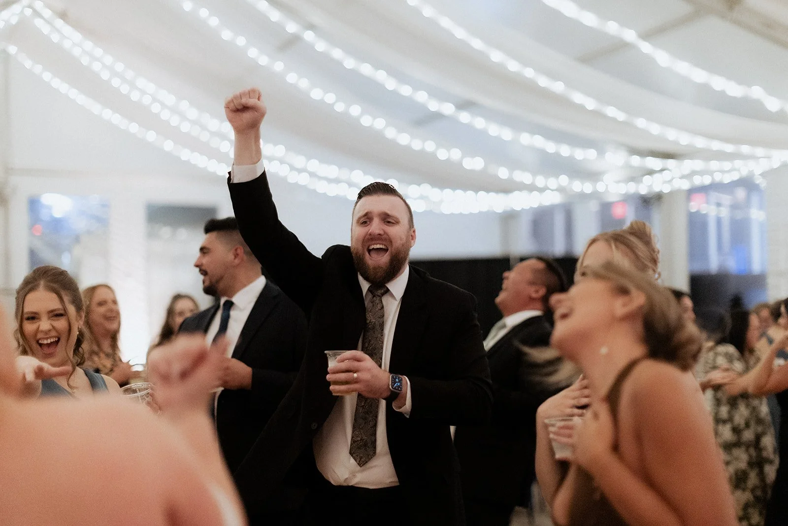 Wedding guests dancing with their arms raised at the New England Aquarium