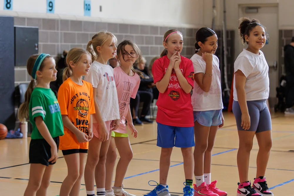 Young girls receiving instruction during a Fundamentals First girls basketball class at Coach Deon Basketball