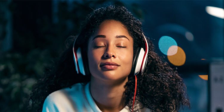african-woman-listening-to-music-with-earphones-while-relaxing-750x375.jpg