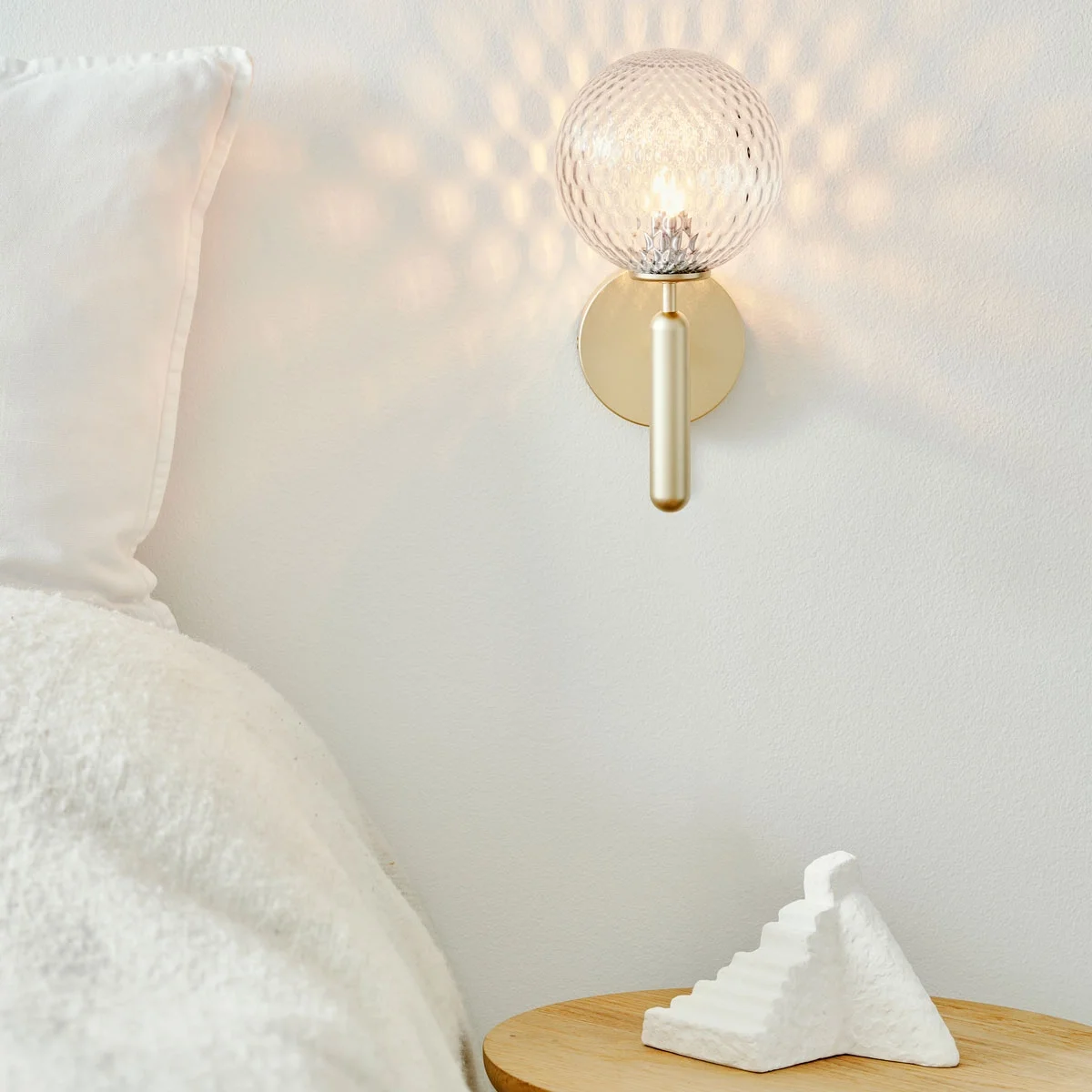 Lifestyle image of the Miira Wall by Nuura, featuring optic glass and brass finish.