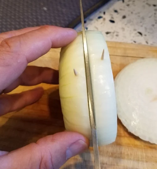 Step 2: Carefully slice midway between the toothpicks, across the grain of the onion.