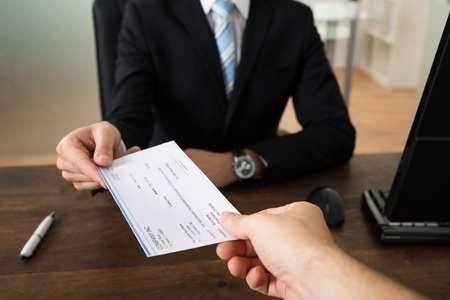 44315690_S_wages_pay_check_corporate_business_man_woman_hands_receiving_money_office_desk.jpg