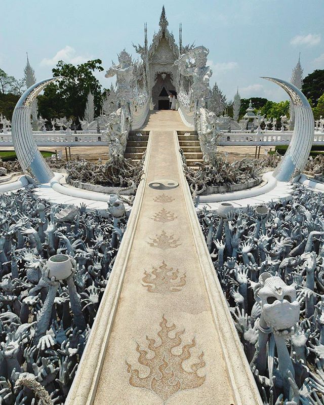 Wat Rong Khun, The White Temple In Chang Rai. Chalermchai Kositpipat, is the Thai visual artist who designed and renovated the White Temple. The temple was opened to the public in 1997. It is 15km south of Chang Rai city.
You can combine a trip to the White Temple with a visit to the Blue Temple or the Baandam Museum or Black House.
Our favorite hotel is @lemeridienchangrai
It’s a quiet hotel with beautiful grounds.
The photograph features the bridge of "the cycle of rebirth”. In front of the bridge are hundreds of outreaching hands that symbolize unrestrained desire. The bridge symbolizes that the way to happiness is to forgo temptation, greed and desire.
Follow us @optionescape for more travel tips.
Please feel free to ask us any questions about our experiences abroad. We were not sponsored for this trip. We paid our own way and our recommendations and opinions here are our own.
#thailandtravel #amazingthailand #whitetemplechiangrai