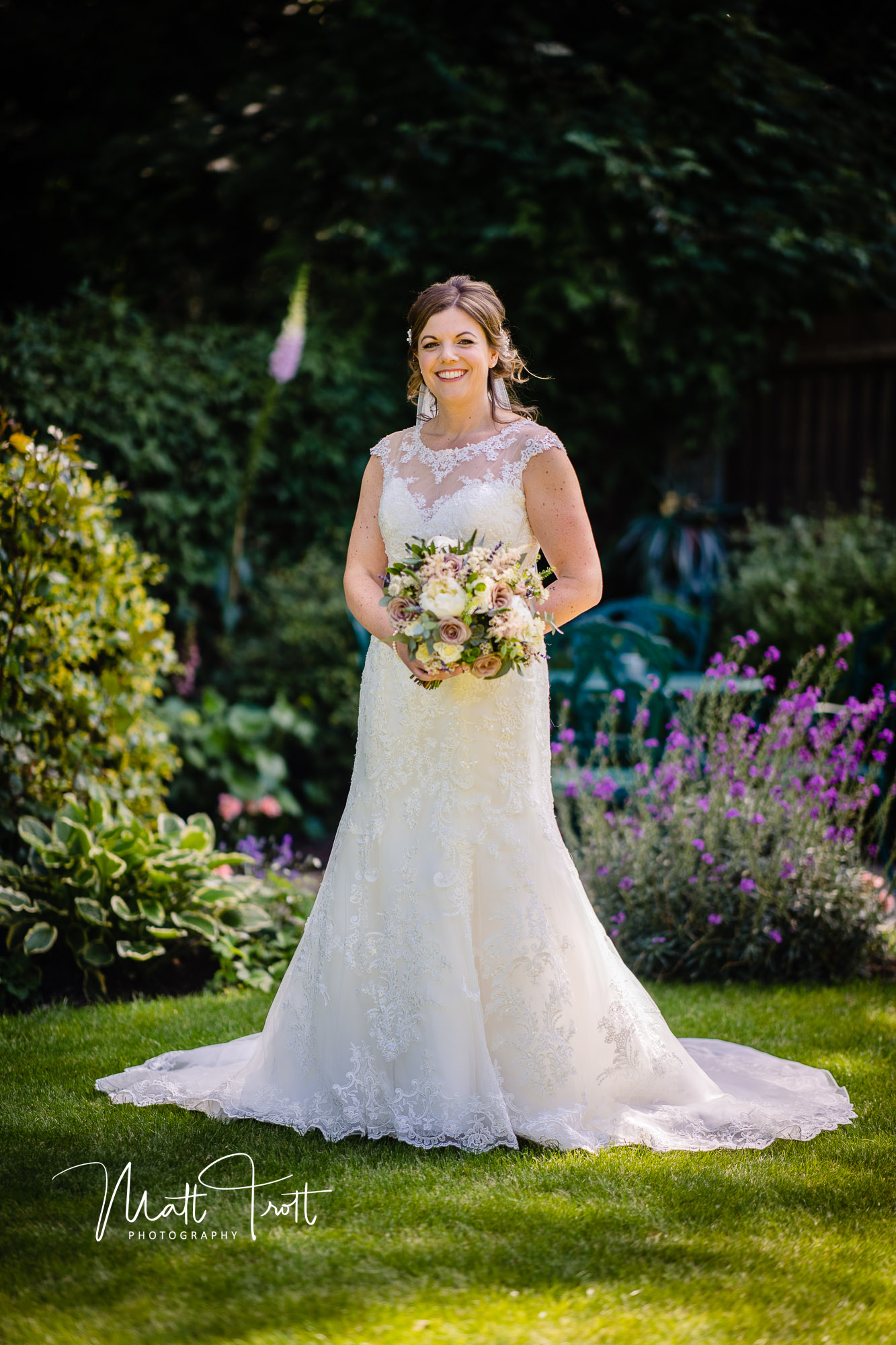 Bridal portrait in the garden with bride smiling and holding flowers