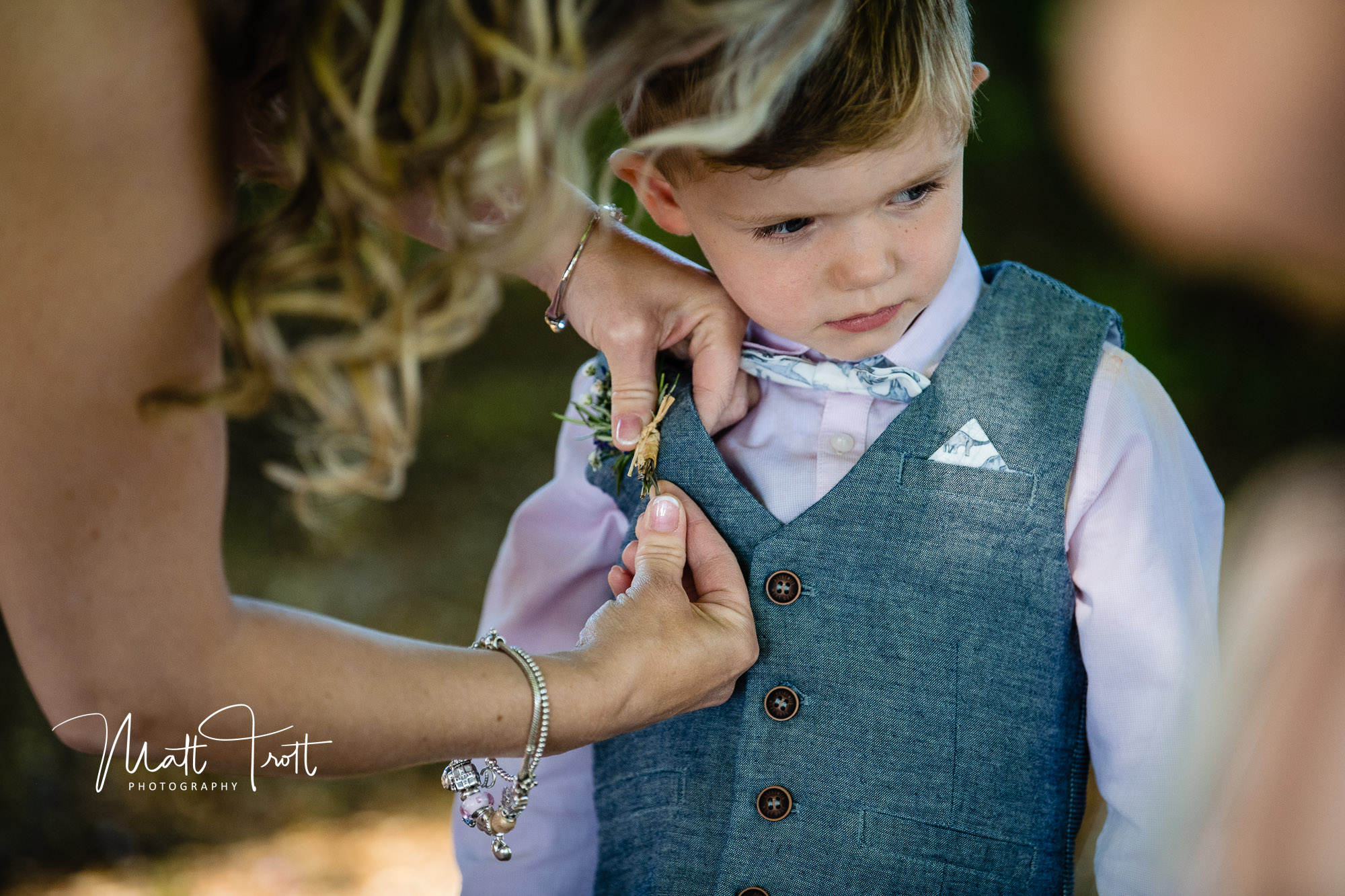 Young boy having a buttonhole flower attached to his suit