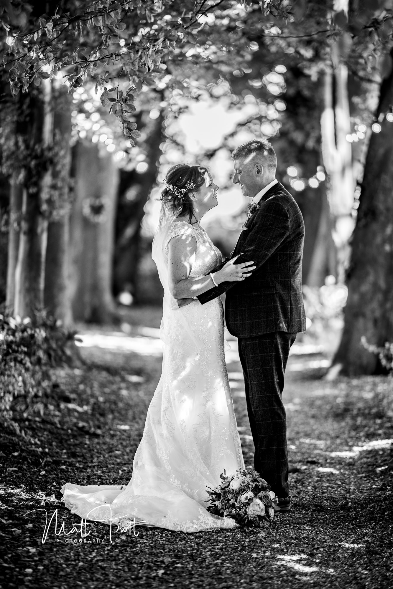 Bride and groom in the trees looking at each other and smiling at crown lodge kent