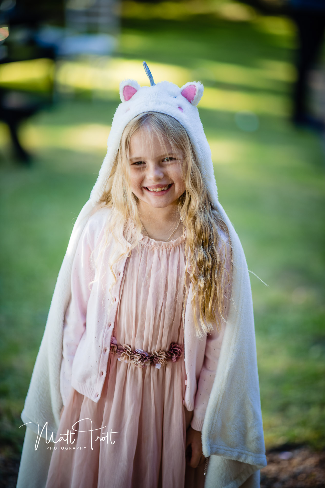 Young flower girl at a wedding with a unicorn jumper over her head