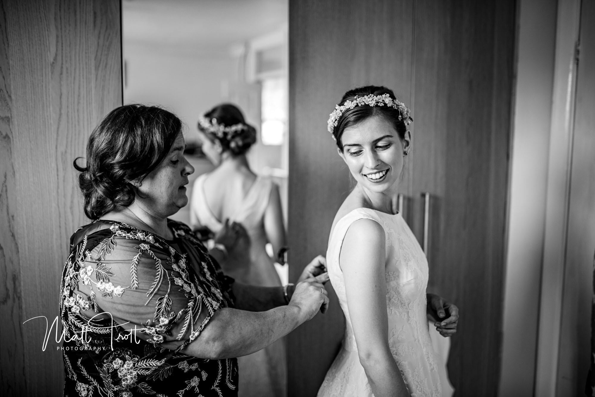 mum helping bride into wedding dress in kent