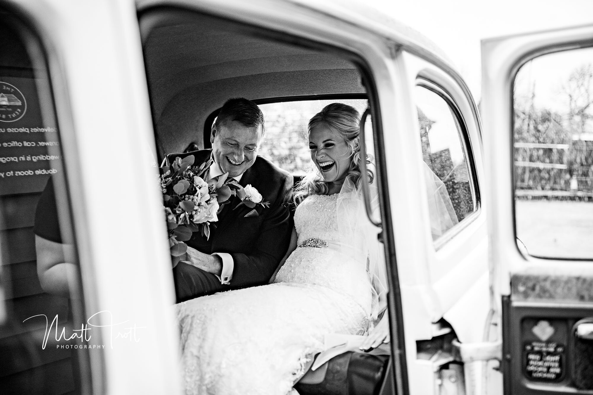 Bride and dad laughing as they get in their wedding car at the old kent barn